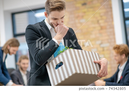 Sad young man with box of personal belongings Sad young man with box of personal belongings 74342805