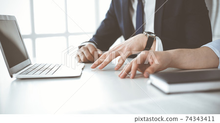 Unknown business people using laptop computer at the desk in modern office. Businessman or male entrepreneur is working with his colleague. Teamwork and partnership concept Unknown business people using laptop computer at the desk in modern office. Businessman or male entrepreneur is working with his colleague. Teamwork and partnership concept 74343411