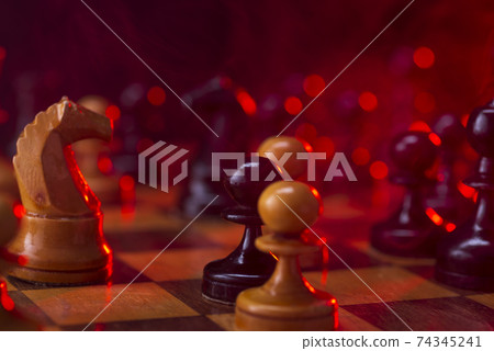 Chess fight, chess pieces on the board, toned in red. Battle fire and smoke 74345241