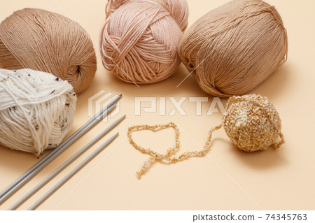Woolen yarns for knitting. Balls of natural wool yarn and knitting needles. 74345763