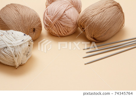 Woolen yarns for knitting. Balls of natural wool yarn and knitting needles. Woolen yarns for knitting. Balls of natural wool yarn and knitting needles. 74345764