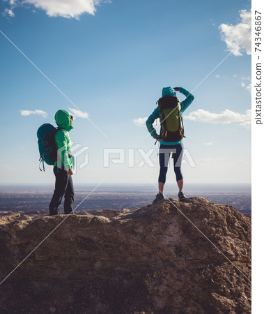 Two women backpackers hiking on sand desert dunes 74346867