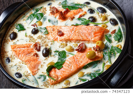 Tuscan salmon with cream sauce on a black dish Tuscan salmon with cream sauce on a black dish 74347123
