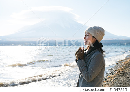 A woman looking at the scenery with a smartphone on the shore of Lake Yamanaka in winter 74347815