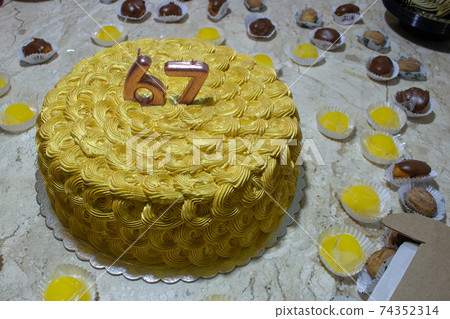 Golden birthday cake covered in chantilly surrounded by sweeties 74352314