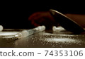 MACRO: Drug addiction. Syringe, Sprinkled white powder. Human hand on background. 74353106