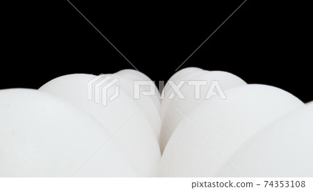 MACRO: Rows of fresh white chicken eggs on black background. 74353108