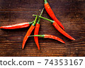 Group of chilli peppers on wood background 74353167