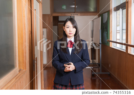 站在走廊與智能手機的高中女孩高中學生 站在走廊與智能手機的高中女孩高中學生 74355316