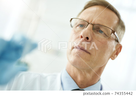 Handsome male doctor in glasses on white blurred background Handsome male doctor in glasses on white blurred background 74355442