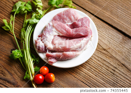 Fresh pork on wooden, raw pork meat on white plate with coriander herbs and spices tomato vegetables. Fresh pork on wooden, raw pork meat on white plate with coriander herbs and spices tomato vegetables. 74355445