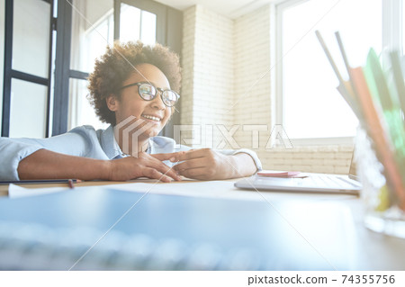Excited teen girl smiling, using laptop having online lesson via video chat app while studying from home 74355756