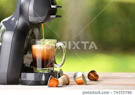 Coffee machine making coffee with capsules on wooden table 74355796