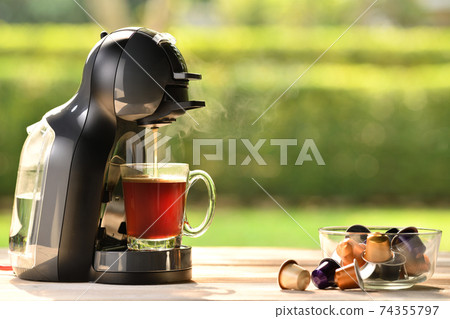Coffee machine making coffee with capsules on wooden table 74355797