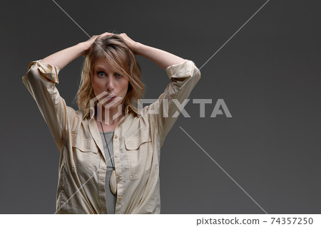 Shocking news. Millennial caucasian woman holding her head with both hands, exclaiming shock, grey background Shocking news. Millennial caucasian woman holding her head with both hands, exclaiming shock, grey background 74357250