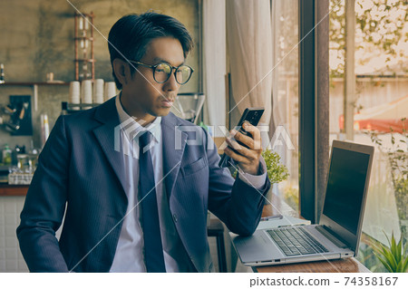 Front Right Asian Businessman Wear Glasses Using Smartphone in Vintage Tone Front Right Asian Businessman Wear Glasses Using Smartphone in Vintage Tone 74358167