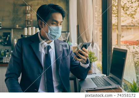 Front Right Asian Businessman Wear Face Mask Using Smartphone in Vintage Tone Front Right Asian Businessman Wear Face Mask Using Smartphone in Vintage Tone 74358172