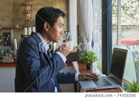 Right Asian Businessman Hold Coffee Cup and Typing Laptop Right Asian Businessman Hold Coffee Cup and Typing Laptop 74358208