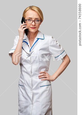 Portrait of a female doctor ornurse talking on the mobile phone 74358600