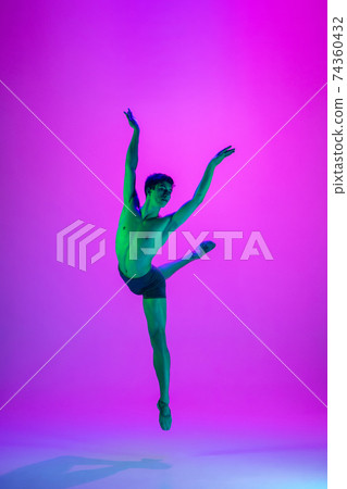 Young and graceful ballet dancer isolated on purple studio background in neon light. Art, motion, action, flexibility, inspiration concept. 74360432