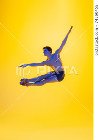 Young and graceful ballet dancer isolated on yellow studio background in neon light. Art, motion, action, flexibility, inspiration concept. Young and graceful ballet dancer isolated on yellow studio background in neon light. Art, motion, action, flexibility, inspiration concept. 74360458