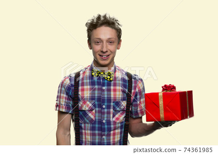 Portrait of smiling boy with bowtie holding a red gift box. 74361985