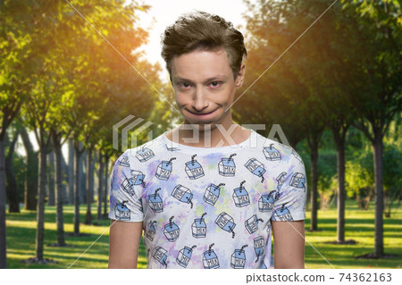 Portrait of handsome offended teen boy in the park. 74362163