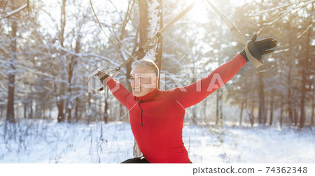 Total resistance fitness. Mature man working out with fit system, training with suspension straps in snowy winter forest Total resistance fitness. Mature man working out with fit system, training with suspension straps in snowy winter forest 74362348