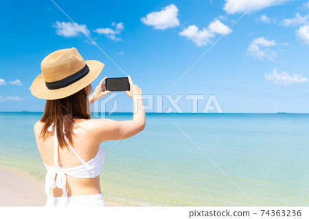 Asian woman in bikini enjoys summer vacation photographing beautiful sea in Thailand 74363236