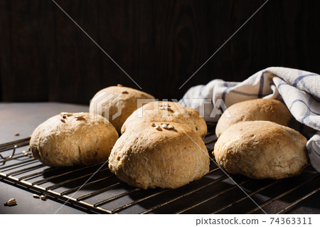 Homemade wholemeal rye wheat buns with seeds on wooden table, dark rustic background. Homemade wholemeal rye wheat buns with seeds on wooden table, dark rustic background. 74363311