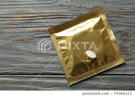 Condom with pin on wooden background, space for text 74366323