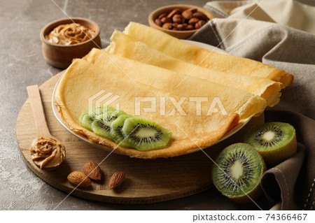Concept of breakfast with crepes with kiwi, peanut butter and nuts on gray background 74366467