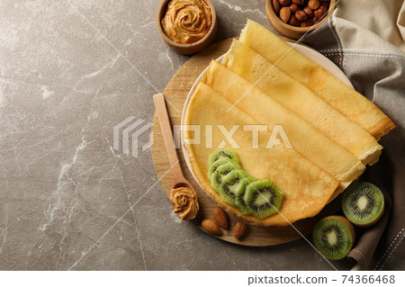 Concept of breakfast with crepes with kiwi, peanut butter and nuts on gray background Concept of breakfast with crepes with kiwi, peanut butter and nuts on gray background 74366468