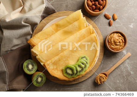 Concept of breakfast with crepes with kiwi, peanut butter and nuts on gray background Concept of breakfast with crepes with kiwi, peanut butter and nuts on gray background 74366469
