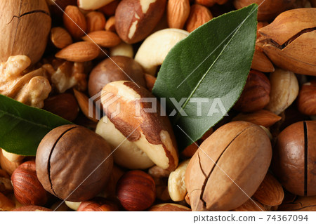 Different tasty nuts on whole background, close up Different tasty nuts on whole background, close up 74367094