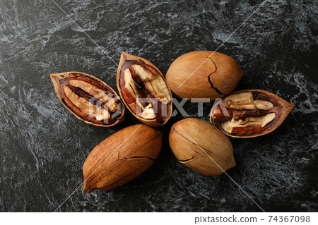 Pecan nuts on black smokey background Pecan nuts on black smokey background 74367098