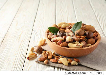 Wooden bowl with different tasty nuts on wooden background Wooden bowl with different tasty nuts on wooden background 74367099