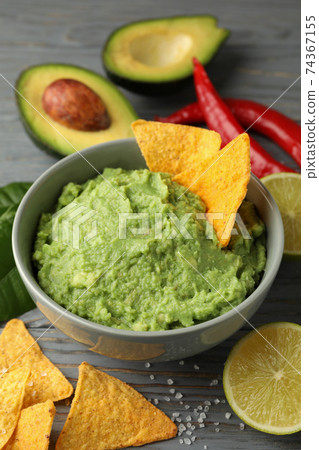 Concept of tasty eating with bowl of guacamole on wooden background Concept of tasty eating with bowl of guacamole on wooden background 74367155
