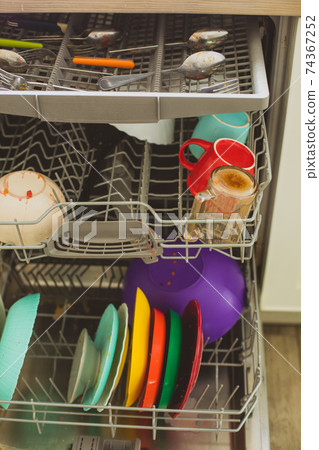 Putting dirty plates in the dishwasher after dinner 74367252