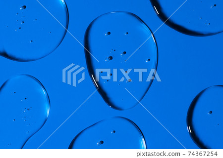 Transparent Gel drops forming background or pattern. Gel drops on blue background Virus protection or cosmetics concept. 74367254