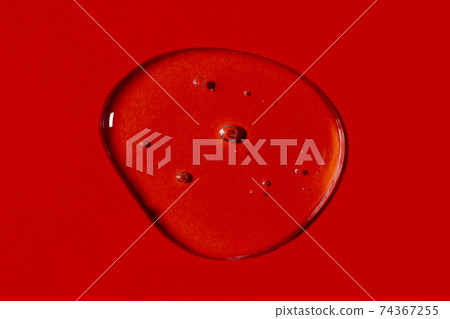 Clear transparent liquid gel drop or smear isolated on vivid red background. Top view. Virus protection or cosmetics concept. Serum texture. Clear transparent liquid gel drop or smear isolated on vivid red background. Top view. Virus protection or cosmetics concept. Serum texture. 74367255