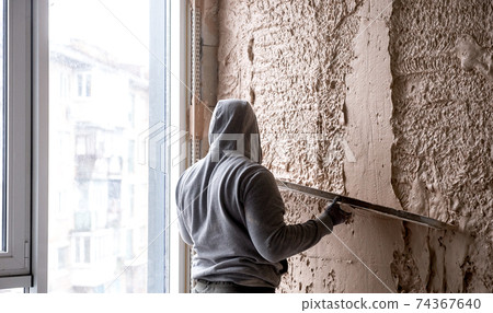Machine plaster. Walls with gypsum plaster or cement plaster. Plasterer operating man sprayer equipment machine. Construction worker puts a finishing touch on the wall. 74367640