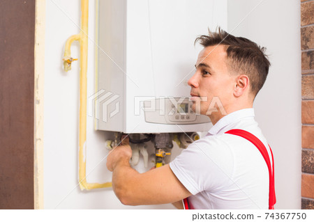The plumber works with boiler at the kitchen 74367750