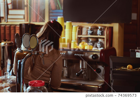 View from the back of female barista preparing coffee in professional coffee machine 74369573