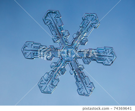 Snowflake on smooth gradient background. Macro photo of real snow crystal on glass surface. This is small snowflake with unusual pattern. Snowflake on smooth gradient background. Macro photo of real snow crystal on glass surface. This is small snowflake with unusual pattern. 74369641