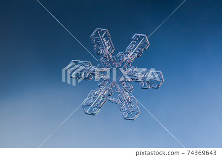 Snowflake on smooth gradient background. Macro photo of real snow crystal on glass surface. This is small snowflake with unusual pattern. Snowflake on smooth gradient background. Macro photo of real snow crystal on glass surface. This is small snowflake with unusual pattern. 74369643
