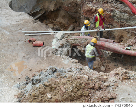 SEREMBAN, MALAYSIA -SEPTEMBER 28, 2016: Construction workers install and fixing underground utility and services pipe. Trenches were dug to the required level for them to do their works.   74370040