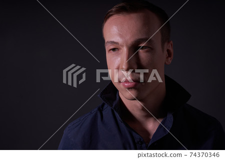 Beautiful young guy on a black background in the Studio 74370346