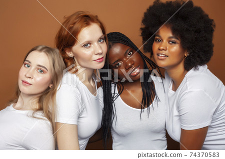 young pretty caucasian, afro, scandinavian woman posing cheerful together on brown background, lifestyle diverse nationality people concept 74370583