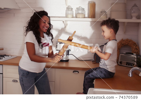 young pretty african american mother with little cute son on kitchen in morning preparing breakfast, lifestyle people concept 74370589